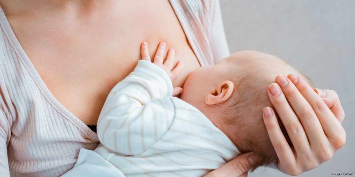 Madre che allatta il proprio neonato tenendolo tra le braccia in un momento di contatto e cura durante l’allattamento.