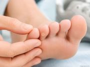 Dettaglio di un occhio di pernice su un dito del piede mentre viene osservato con la mano. Immagine che richiama il rapporto tra pressione, scarpe e movimento del piede.