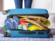 Valigia pronta per le vacanze con abiti e accessori estivi. Un'immagine che richiama l'idea di rallentare, dedicare tempo a sé stessi e prendersi una pausa dai ritmi quotidiani.